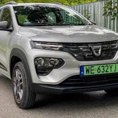 Srebrna Dacia Spring z zieloną tablicą rejestracyjną. Ten elektryczny samochód oferuje dobry zasięg na jednym ładowaniu.