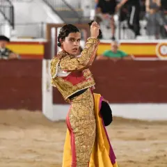 Joao Ferreira, banderillero, con traje de luces dorado y rojo, sostiene un capote en la plaza de toros.