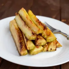 Zucchine in carpione dorate e succulente, impilate su un piatto bianco, pronte per essere gustate.
