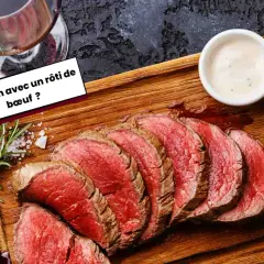 Un verre de vin rouge accompagne un rôti de bœuf tranché, prêt à être dégusté. Une question se pose : quel vin choisir pour ce plat savoureux ?