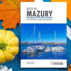 Okładka przewodnika po Mazurach z widokiem na żaglówki i jesienne dekoracje.