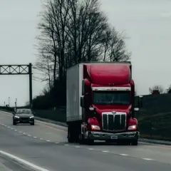 Czerwony tir na autostradzie, doskonały przykład leasingu tir. W tle inne ciężarówki i samochody osobowe.