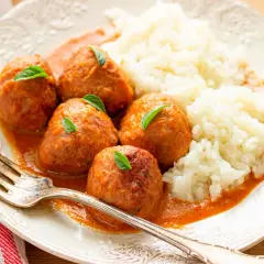 Albondigas a la jardinera con arroz blanco, decoradas con hojas verdes. Un plato casero y apetitoso.