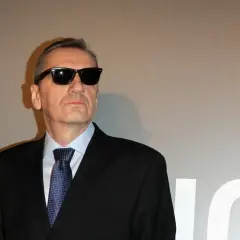 Władysław Pasikowski w czarnym garniturze i okularach przeciwsłonecznych, gotowy na premierę swojego kolejnego filmu.