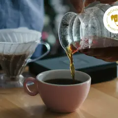 Frisch gebrühter Kaffee fließt aus einer Glaskaraffe in eine rosa Tasse. Ein V60-Filter mit Kaffee steht bereit. Das perfekte Kaffee Rezept für Genießer.