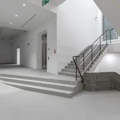 Wnętrze muzeum sztuki współczesnej Kraków: projekcja wideo, betonowe schody i rzeźba.
