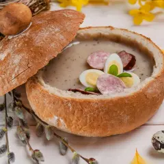 Zupa biały barszcz w chlebie, ozdobiona jajkiem i kiełbasą. Idealna, gdy zastanawiasz się, jak odkwasić zupę.