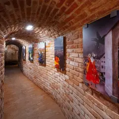 Galeria w ceglanym korytarzu prezentuje brneńskie nietypowe atrakcje: obrazy z legendarnymi stworzeniami i miejskimi pejzażami.