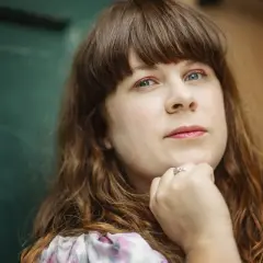 Ann Edliden, med sitt långa, bruna hår och blå ögon, vilar hakan i handen.