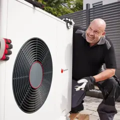 Un technicien souriant aide à installer une pompe à chaleur air air, un système efficace pour le confort de votre maison.