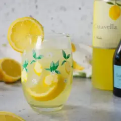 En uppfriskande limoncello spritz med citronklyftor i ett glas med citrontryck. Bredvid står en flaska prosecco och en flaska limoncello.