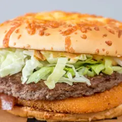 Podwójny drwal kcal: soczysty kotlet wołowy, chrupiąca panierka, świeża sałata i ser na bułce z sezamem.