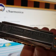 Harmonijka Marine Band DELUXE, z wygrawerowanymi nutami i numerami, gotowa do zagrania melodii.