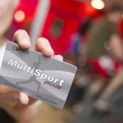 Karta MultiSport Plus w ręce na tle siłowni.