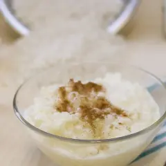 Schüssel mit Milchreis, Zimt, Butter, Zimtstangen und Reis. Die Frage, wie lange ist Milchreis nach MHD haltbar, beschäftigt viele.