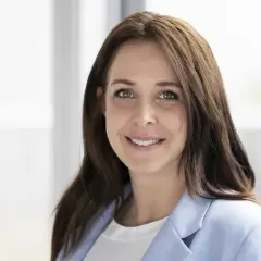 Porträt einer lächelnden Frau mit braunen Haaren und einem hellblauen Blazer. Dies ist eine klare Definition eines Porträts.