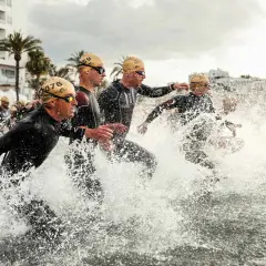 Sportler stürmen ins Wasser für einen Triathlon Kurzdistanz.