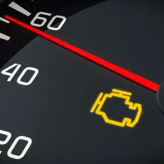 Cruscotto auto con spia motore accesa. L'ago del contagiri indica una velocità bassa, ma la spia gialla del motore è un segnale di allarme.
