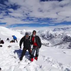 Dwóch alpinistów na śnieżnym szczycie Mera Peak, z zapierającym dech w piersiach widokiem na Himalaje.