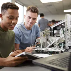 Dos estudiantes trabajan en un robot, aplicando la metodología STEM para resolver un desafío de ingeniería.