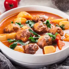 Zupa klopsowa babci: aromatyczne klopsiki w pomidorowym sosie z ziemniakami i natką pietruszki.