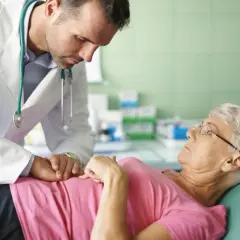 Lekarz bada pacjentkę, która skarży się na przelewanie w brzuchu. Delikatnie dotyka jej brzucha, próbując zdiagnozować przyczynę dolegliwości.