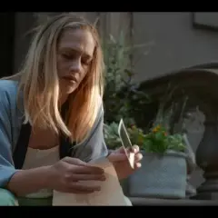 Jemima Kirke sitter på trappan och läser ett brev med en kniv i handen. En scen från filmer och tv-program med Jemima Kirke.