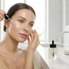 Donna applica siero viso, scopri i benefici della niacina per una pelle luminosa e idratata.