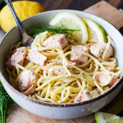 Schüssel mit cremigen Nudeln mit Lachs, garniert mit Zitronenscheiben und Dill. Ein Genuss für Feinschmecker!