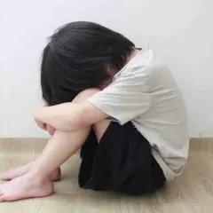 Bambino rannicchiato, un'immagine che evoca la necessità di capire come aiutare un figlio depresso.