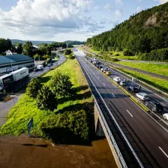 Trafikkaos vid en översvämmad rastplats. Bilar står stilla på motorvägen, en lastbil har fastnat i vattnet.