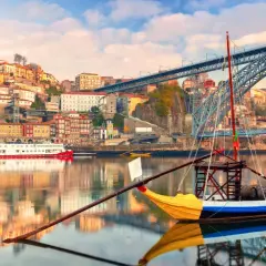 Barcos tradicionales navegan por el río Duero, con la colorida Ribeira y el puente Dom Luís I al fondo. Perfectas rutas cerca de Oporto para explorar.