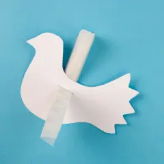 Eine weiße Papier-Friedenstaube wird mit Klebeband befestigt. Bastelanleitung für eine Friedenstaube.