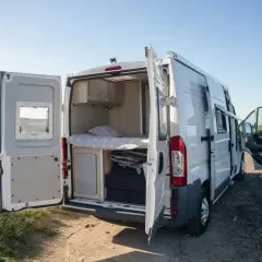 Trzy Mitsubishi L300 Delica D:5 w różnych kolorach i wersjach, na białym tle.
