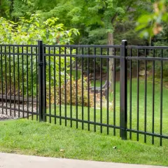 A newly completed metal fence installation encloses a lush green lawn and garden area, providing a sleek and secure boundary.