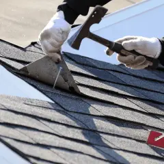 Ręce w rękawiczkach zdejmują starą papę z dachu za pomocą łopatki. Zastanawiasz się, czym rozcieńczyć lepik na zimno?