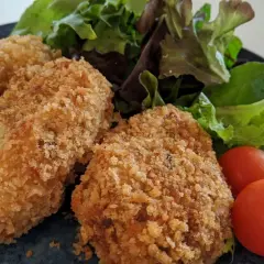 Golden potato croquettes served with fresh salad and cherry tomatoes.