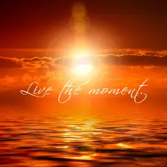 Tramonto infuocato sull'oceano, con la scritta "Live the moment" che invita a vivere il presente.