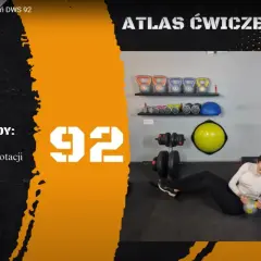 Kobieta wykonuje Russian twist z odważnikiem. Na ekranie widnieje napis "Russian Twist" i numer 92.