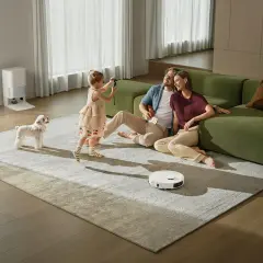 Familia feliz disfrutando de su hogar mientras un robot aspirador limpia. Las ventajas de la domótica se reflejan en este momento de paz y comodidad.