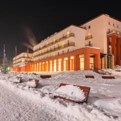 Zimowy wieczór w sanatorium godnym polecenia. Ośnieżone ławki i drzewa tworzą bajkową scenerię.