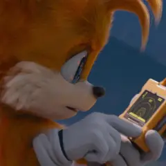 Tails Sonic, z dwoma ogonami, analizuje dane na żółtym urządzeniu.