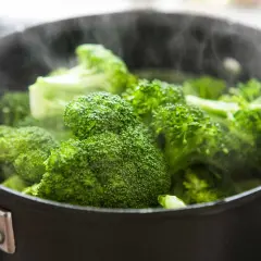 Frischer Brokkoli dämpft in einem Topf. Die Frage "wie lange muss Brokkoli kochen" wird hier visuell beantwortet: kurz, bis er zartgrün ist.