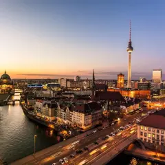 Berlin vid solnedgången. En bro leder över floden, med bilar som susar förbi. En fantastisk utsikt över Tyskland, som kan vara en del av en resa från Danmark.