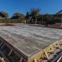 Der Schalung Aufbau für eine Betonplatte ist sichtbar. Holzstützen und Bretter formen den Rand der frisch gegossenen Bodenplatte.