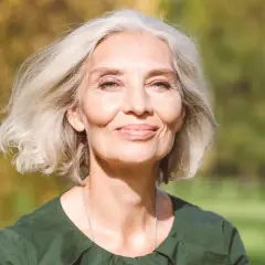 Mujer sonriente con cabello rubio platino, ideal para matizar canas. Su piel irradia luz natural.