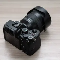Aparat Sony a7v z obiektywem 24-105 mm G OSS na drewnianym blacie.