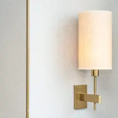 Aplique de pared moderno con pantalla de tela beige, montado en una pared con textura gris.