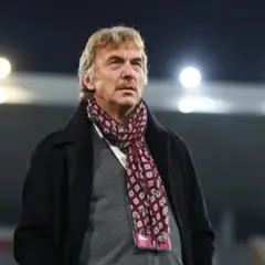 Zbigniew Boniek w płaszczu i szaliku na tle stadionu.