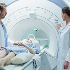 Pacjentka leży w aparacie do rezonansu magnetycznego, gdzie lekarze przygotowują badanie z kontrastem.